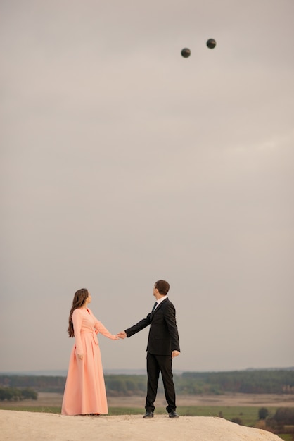 Bride and groom with large helium balloons at wedding walk enjoy each other outdoor with beautiful view at sunset