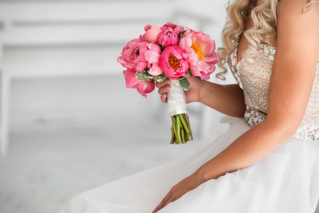 Bride holding beautiful wedding bouquet of pink peonies