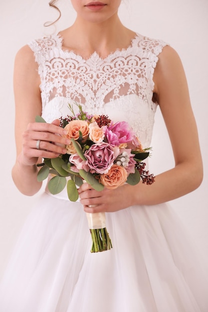 Bride holding wedding bouquet on white background closeup