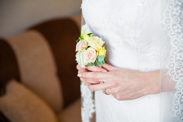 Bride holding wedding boutonniere in hands. Bride morning