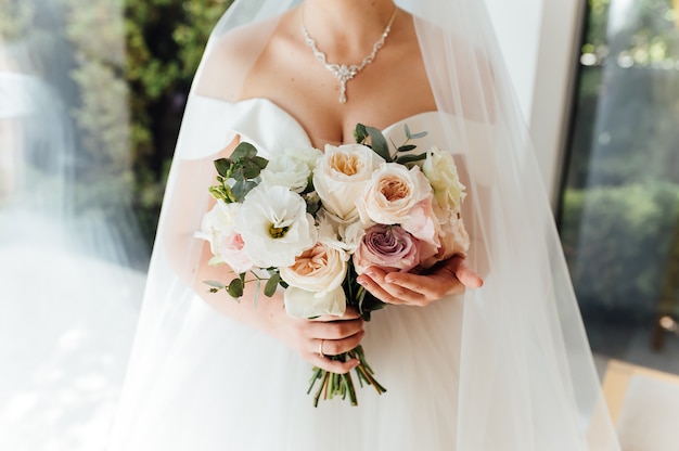 Photo bride holding white wedding bouquet of roses and love flower