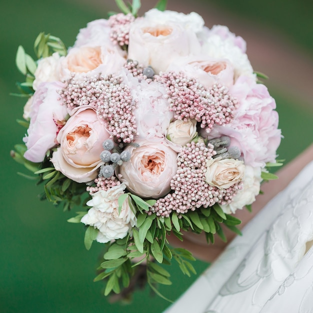 The bride holds a beautiful wedding bouquet of peonies