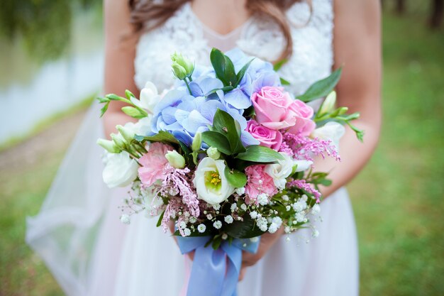 The bride holds a flowers bouquet in her hands