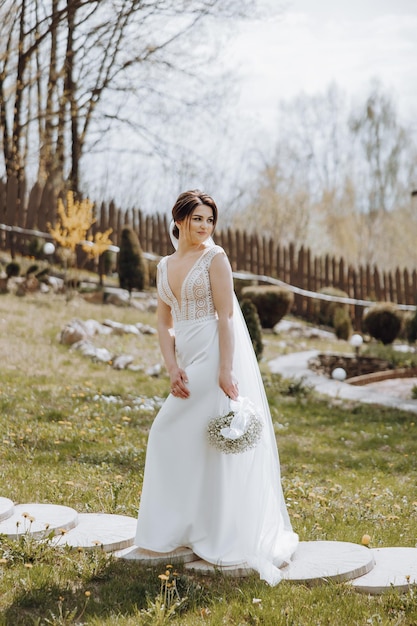 A bride is standing in a field with a bouquet of flowers