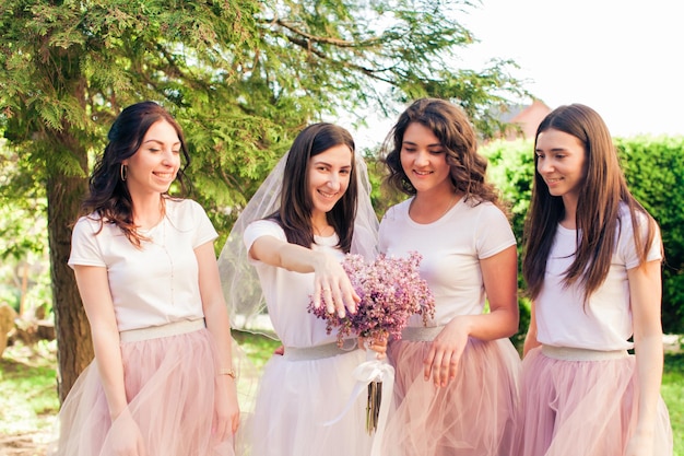 The bride jokes with her bridesmaids and shows her wedding ring