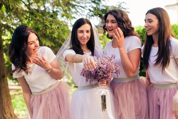 The bride jokes with her bridesmaids and shows her wedding ring