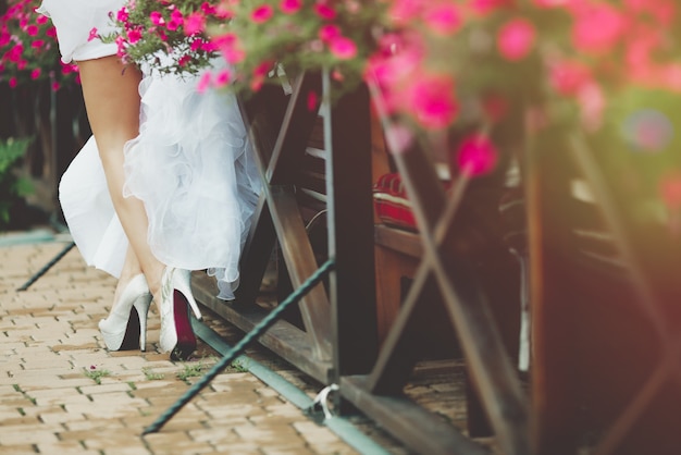 Bride legs near fence with flowers closeup