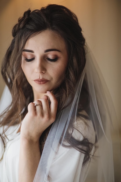 Bride morning preparation. Beautiful bride in white wedding negligee