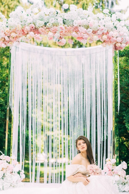 Bride near wedding arch with flowers