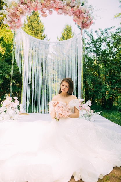 Bride near wedding arch with flowers