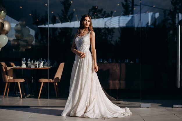 A bride poses in front of a glass wall