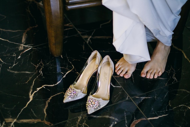 the bride puts on her wedding shoes in the morning before the wedding ceremony, the bride's legs