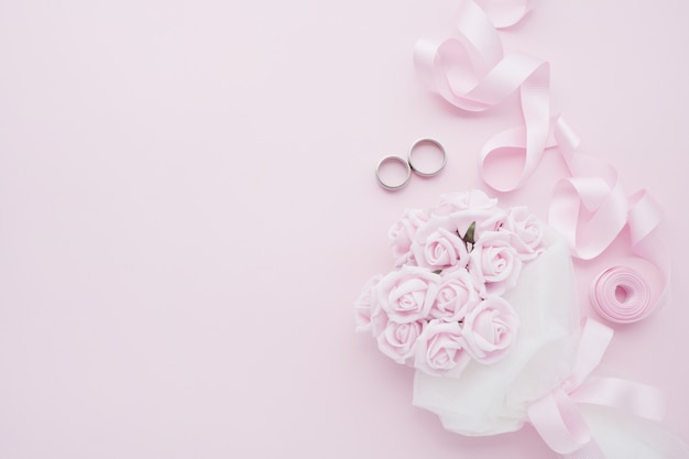 Bride's bouquet of pink roses, wedding rings and pink ribbon