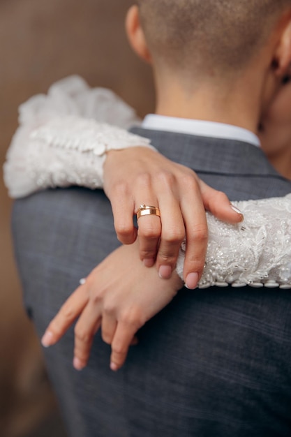 Photo bride's hands behind husband's head during a kiss gold wedding rings on fingers kiss of lovers and sensual embrace of a girl