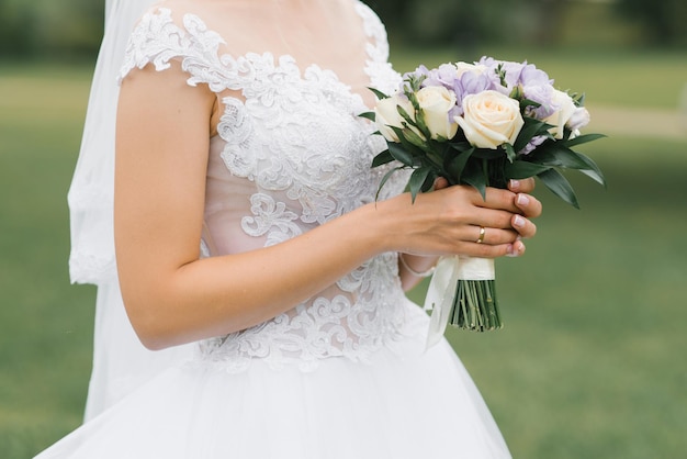 The bride's wedding bouquet of milk roses and lilac eustoms in the hands of the bride