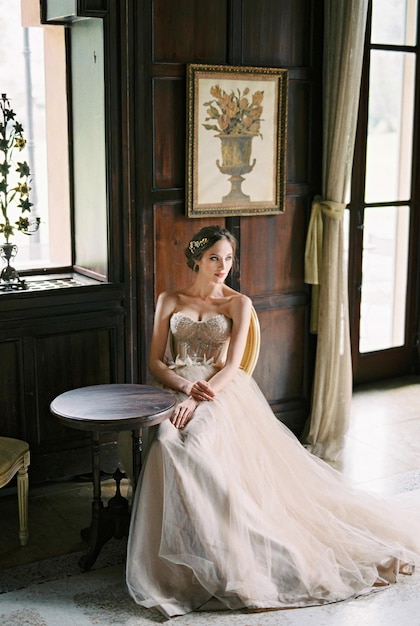 Bride sits at a table near the window of an old villa Como Italy