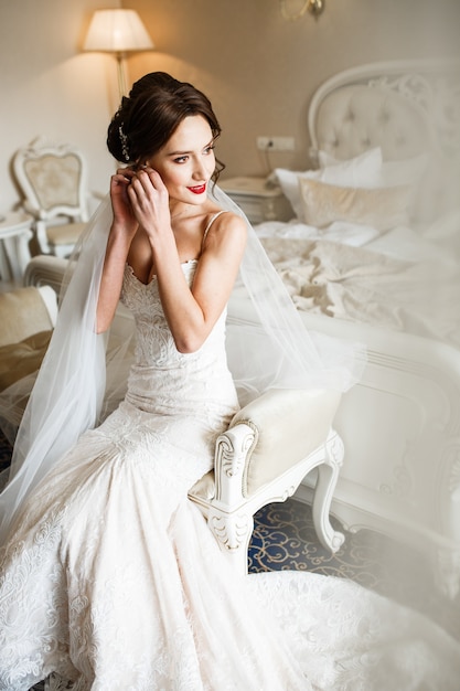 Bride sits in wedding dress on little white sofa