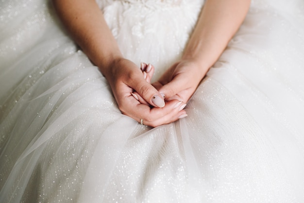 Bride sitting in her wedding dress, close up of hands