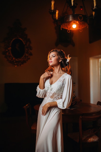 A bride in underwear and a white robe in the interior of a Villa