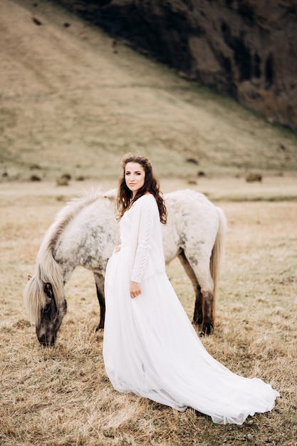 Bride walks across the field next to a white horse