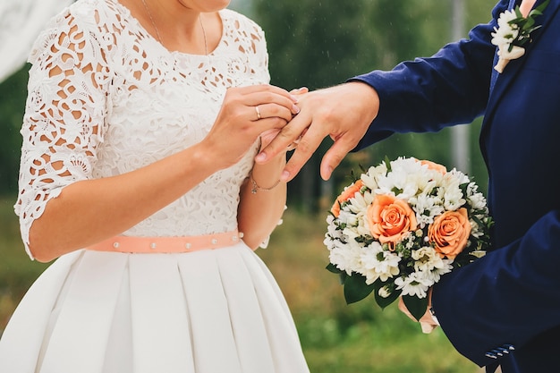 Bride wears a ring on groom finger at wedding