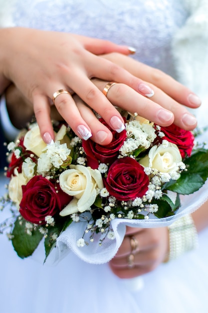 Photo bride in wedding dress and groom with a bouquet of flowers and greens in hands.