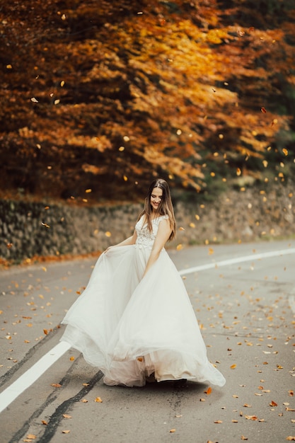 Photo bride in a wedding dress is spinning on the road