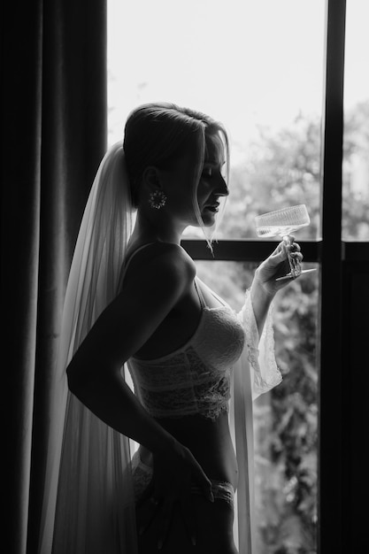 Photo a bride in a wedding dress is standing by a window