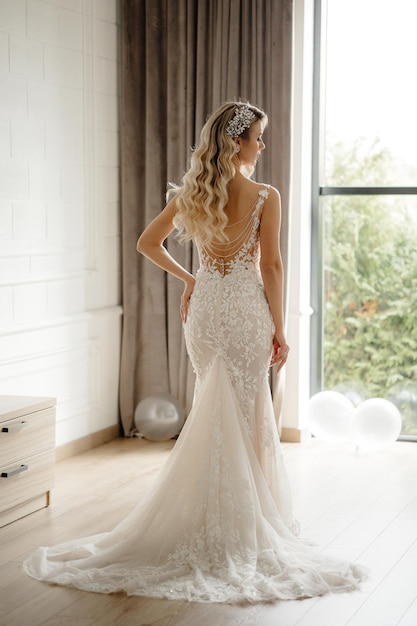 Bride in a wedding dress standing in front of a window