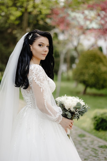 A bride in a wedding dress stands in a garden