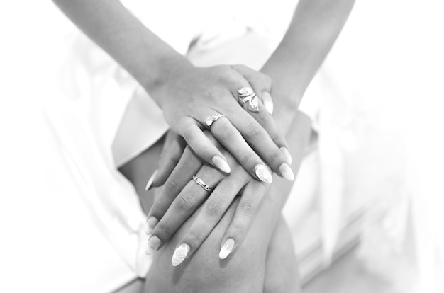 Bride in white clothes near the window Beautiful manicure Elegant nails Golden rings Wedding jewellery Black and white