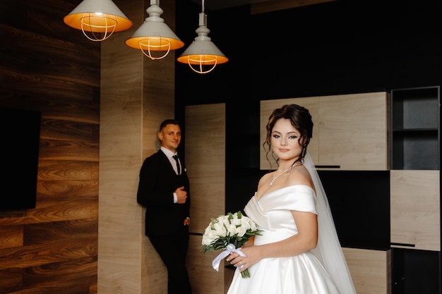 a bride in a white dress is standing in front of a wall with lights