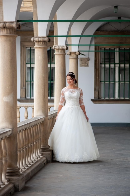 A bride in a white dress stands on a balcony