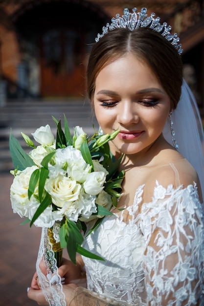 Bride in a white dress with a bouquet in her hands and a crown on her head