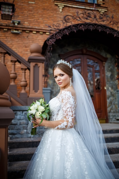 Bride in a white dress with a bouquet in her hands and a crown on her head