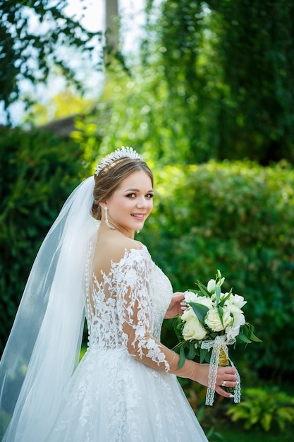 Bride in a white dress with a bouquet in her hands and a crown on her head