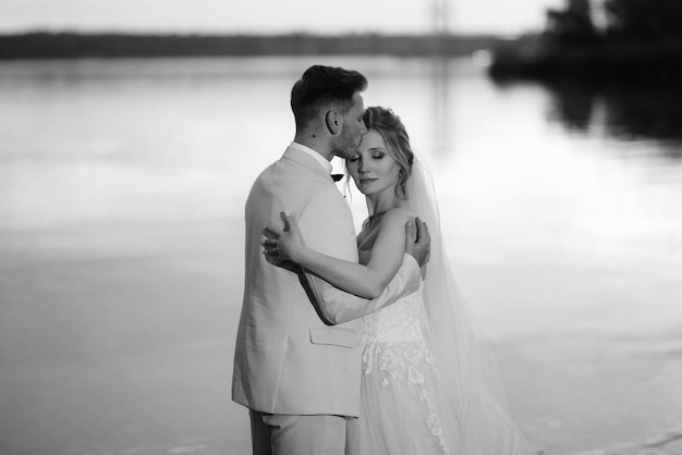 Bride in a white puffy dress and the groom in t on the river bank