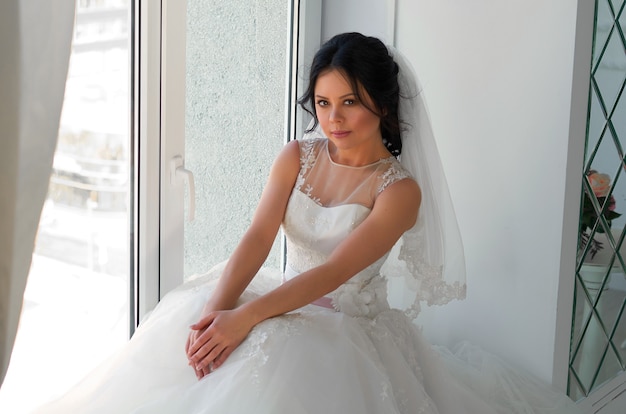 A bride in a white wedding dress in a bright room