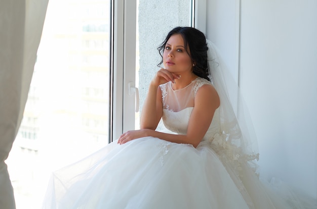 A bride in a white wedding dress in a bright room