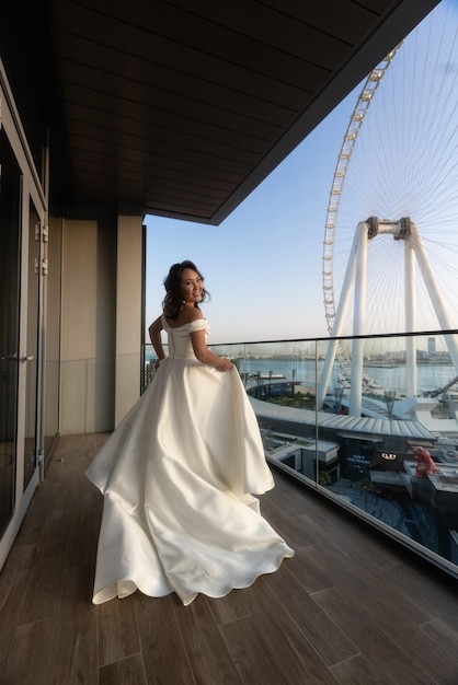 Bride in a white wedding dress standing in front of a ferris wheel