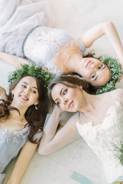 Bride with bridesmaids are lying on the white floor