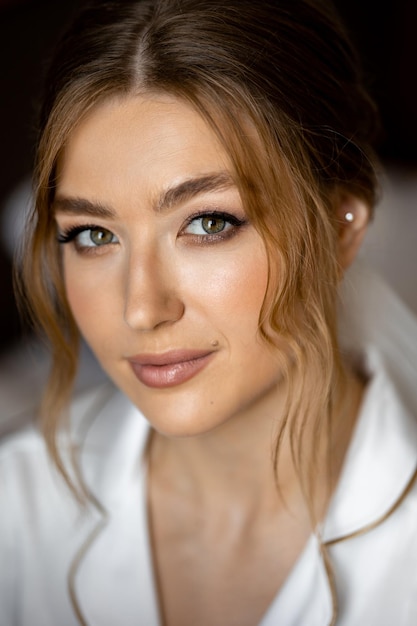 A bride with a white shirt and green eyes looks into the camera