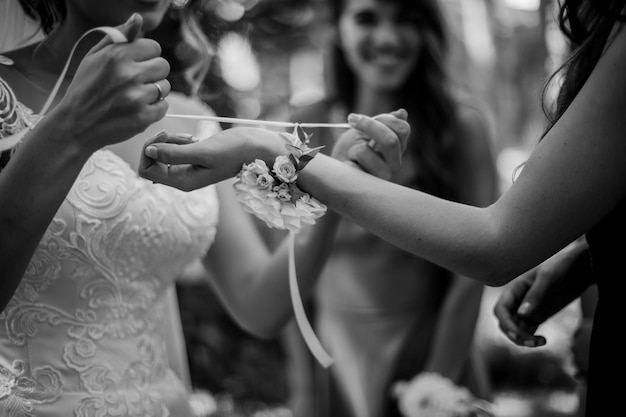 the brides hands tying the wedding wristband on the hand of the bridesmaidblack and white photo