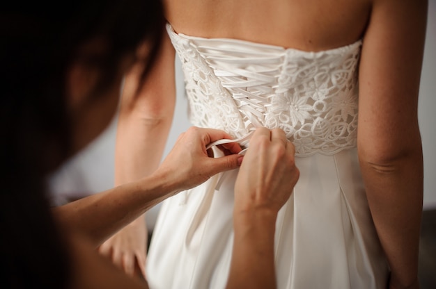 Bridesmaid making bow-knot on the back of brides wedding dress