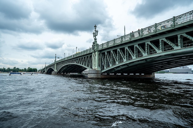 Bridge A low metal bridge across the river in cloudy weather in gloomy dark colors St Petersburg