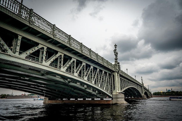 Bridge A low metal bridge across the river in cloudy weather in gloomy dark colors St Petersburg