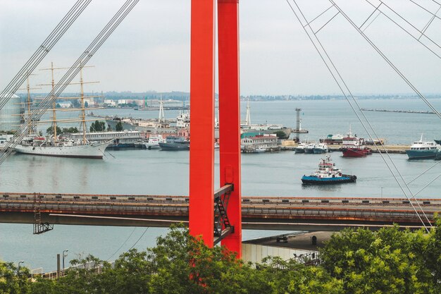 Bridge passing through the river against the background of ships and boats on the pier.