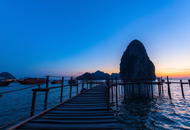 a bridge with a rock in the background and a long pier in the water