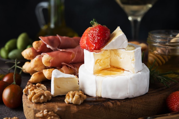 Brie cheese, camembert, grissini, jamon, wine, nuts, honey. Snacks for wine. Italian snacks, close up