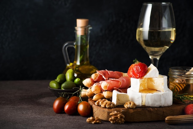 Brie cheese, camembert, grissini, jamon, wine, nuts, honey. Snacks for wine. Italian snacks. Copy space